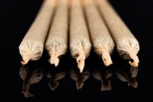Cannabis Marijuana Rolled in Joints on Dark Reflective Background